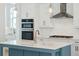 Bright kitchen boasts white cabinets, a blue island, stainless steel appliances, and stylish pendant lighting at 9005 Stern Aly, Johns Island, SC 29455