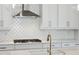 Close up of a kitchen with stainless hood and gas range, white cabinets and subway tile backsplash at 9005 Stern Aly, Johns Island, SC 29455