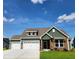 Two-story craftsman style home with stone and green siding, two-car garage, and manicured lawn at 270 Darby Meadow Ln, Ridgeville, SC 29472