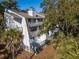 Two-story home with multiple balconies, decks, and exterior stairs, nestled in trees at 279 Driftwood Ln, Edisto Beach, SC 29438