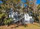 Two-story home with exterior stairs, deck, and landscaping; situated amongst mature trees at 279 Driftwood Ln, Edisto Beach, SC 29438