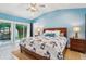 Main bedroom with blue walls, wood bed frame, and access to a private patio at 420 E Erie Ave, Folly Beach, SC 29439