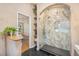Elegant bathroom with marble shower, black tile floor, and wooden shelf at 8517 Falling Leaf Ln, North Charleston, SC 29420