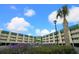 Two-story building with balconies, lush landscaping, and ample parking at 3701 Dock Site Rd # 205, Edisto Beach, SC 29438