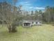 Tan mobile home with covered porch and large yard, surrounded by trees at 139 Yellowstone Ln, Ridgeville, SC 29472