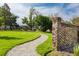 Landscaped pathway and brick wall create inviting entrance to the property with lush greenery and an open lawn at 2038 Ironstone Aly # 17, Charleston, SC 29407