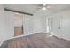 A well-lit bedroom with a ceiling fan, grey flooring and wide doorway with a view to the living area at 2664 Hull St, North Charleston, SC 29405