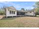 Back exterior view of a two-story modern farmhouse with board and batten siding and a screened-in porch on a partially-wooded lot at 3874 Srevir Rd, Johns Island, SC 29455