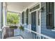 Quaint porch with white railings, gray siding, and black door at 27 Chapel St, Charleston, SC 29403