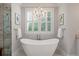 Elegant bathroom with freestanding tub, chandelier, and plantation shutters at 3365 Westphal Dr, Johns Island, SC 29455