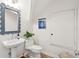 Stylish powder room with pedestal sink, scalloped mirror, and wood-look flooring at 2281 Portside Way, Charleston, SC 29407