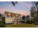 Back exterior of two story home showcasing a large backyard and patio area at sunset at 341 Bridgetown Pass, Mount Pleasant, SC 29464