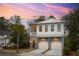 Two-story home exterior; white siding, gray accents, two-car garage, and a charming porch at 341 Bridgetown Pass, Mount Pleasant, SC 29464