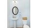Clean and modern bathroom with pedestal sink and round mirror at 2700 Sunrose Ln, Johns Island, SC 29455