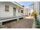 Side view of a charming white cottage with a long front porch and brick pathway at 17 H St, Charleston, SC 29403