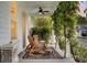 Inviting covered front porch with ceiling fan and cozy rocking chairs amidst lush greenery at 2021 Codorus Ln, Hanahan, SC 29410