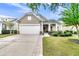 Tan house with white garage door, landscaping, and a covered porch at 459 Eastern Isle Ave, Summerville, SC 29486