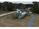 White farmhouse with gray roof, screened porch, and private driveway, surrounded by trees and a pond at 1104 Hitchfield Ln, Awendaw, SC 29429