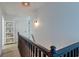 Upper hallway with dark wood railing, shelving unit, and light walls at 33 Cypress St, Charleston, SC 29403