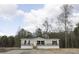 Tan and beige single-wide manufactured home with black windows, wooden steps, and surrounding woodland at 520 Branch Bend Way, Cross, SC 29436