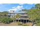 Elevated home showcasing expansive decks and lush landscaping at 153 Dewees Inlet Dr, Dewees Island, SC 29451