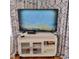 White TV stand with storage, housing a TV and various media components at 209 Palmetto Blvd, Edisto Beach, SC 29438