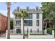 Three-story white modern home with black accents, gated entrance, and palm trees at 100 Murray Blvd, Charleston, SC 29401