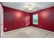Empty bedroom with red walls, beige carpet, and a window at 7468 Northgate Dr, Hanahan, SC 29410