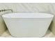 Closeup of a sleek white standalone bathtub with marble-patterned tile surround at 1034 Weeks Lane, Round O, SC 29474