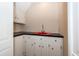 A small basement wet bar with red sink, white cabinets, and black countertop at 108 Fairway Dr, Summerville, SC 29483