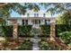 White two-story home with a metal roof, brick pillars, and lush landscaping at 222 Haddrell St, Mount Pleasant, SC 29464
