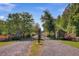 Gated entrance to the property with mature trees and lush landscaping along a gravel driveway for privacy and curb appeal at 6411 China Back Ln, Meggett, SC 29449