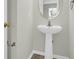 Convenient pedestal sink powder room with a circular mirror at 5211 Fernland Way, North Charleston, SC 29420