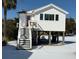 Charming elevated beach cottage with a pink door and snow on the ground at 1306 Palmetto Blvd, Edisto Beach, SC 29438