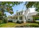 Elegant white home with black-framed windows features a charming porch and lush landscaping at 3324 Westphal Dr, Johns Island, SC 29455