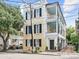 Three-story yellow house with black shutters, white columns, and a gated courtyard at 53 Hasell Street St # H, Charleston, SC 29401