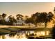 Luxury homes and a pond are nestled on a golf course at sunset at 945 Fish Camp Rd, Charleston, SC 29492