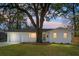 Evening view of a renovated white brick house with a large oak tree in the front yard at 5259 Hartford Cir, North Charleston, SC 29405