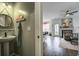 Stylish powder room with pedestal sink, round mirror, and adjacent living room featuring a fireplace and modern furnishings at 221 Trillium Ave, Summerville, SC 29483