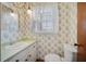 Charming half-bath features a pedestal sink, decorative wallpaper, and updated fixtures at 2830 Wire Rd, Saint George, SC 29477