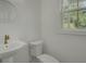 A clean powder room has a pedestal sink, an elegant faucet, a round mirror, and a window for natural light at 637 N Laurel St # 75, Summerville, SC 29483