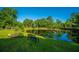 Scenic pond view, featuring a bench and fishing poles, enhanced by lush greenery and clear sky reflections at 788 Awendaw Lakes Blvd, Awendaw, SC 29429
