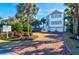 Beautiful two-story home features palm trees, lush landscaping, and a brick driveway at 120 Charleston Blvd, Isle of Palms, SC 29451