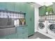 Beautiful laundry room with green cabinets, tile backsplash, and modern washer/dryer at 120 Charleston Blvd, Isle of Palms, SC 29451