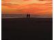 Two people silhouetted against a vibrant sunset over the ocean, creating a peaceful and stunning beach scene at 1402 Camp Rd # 15H, Charleston, SC 29412