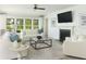 Bright living room features a fireplace, ceiling fan, large windows, and comfortable white furniture at 2094 Cousteau Ct, Johns Island, SC 29455