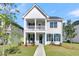 Charming two-story white home with a covered porch and manicured front lawn on a bright sunny day at 232 O'Malley Dr, Summerville, SC 29483
