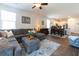 Open-concept living room featuring hardwood floors, ceiling fan, and comfortable seating and modern kitchen in background at 303 Feldspar Ln, Ladson, SC 29456