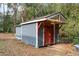 Outdoor shed with red doors, gray siding, and white trim set amongst lush foliage at 3348 River Landing Rd, Johns Island, SC 29455