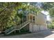 Inviting two-story home, showcasing elevated design and lush surroundings, framed by mature trees and natural light at 8869 Marsh Aire Ln, Edisto Island, SC 29438